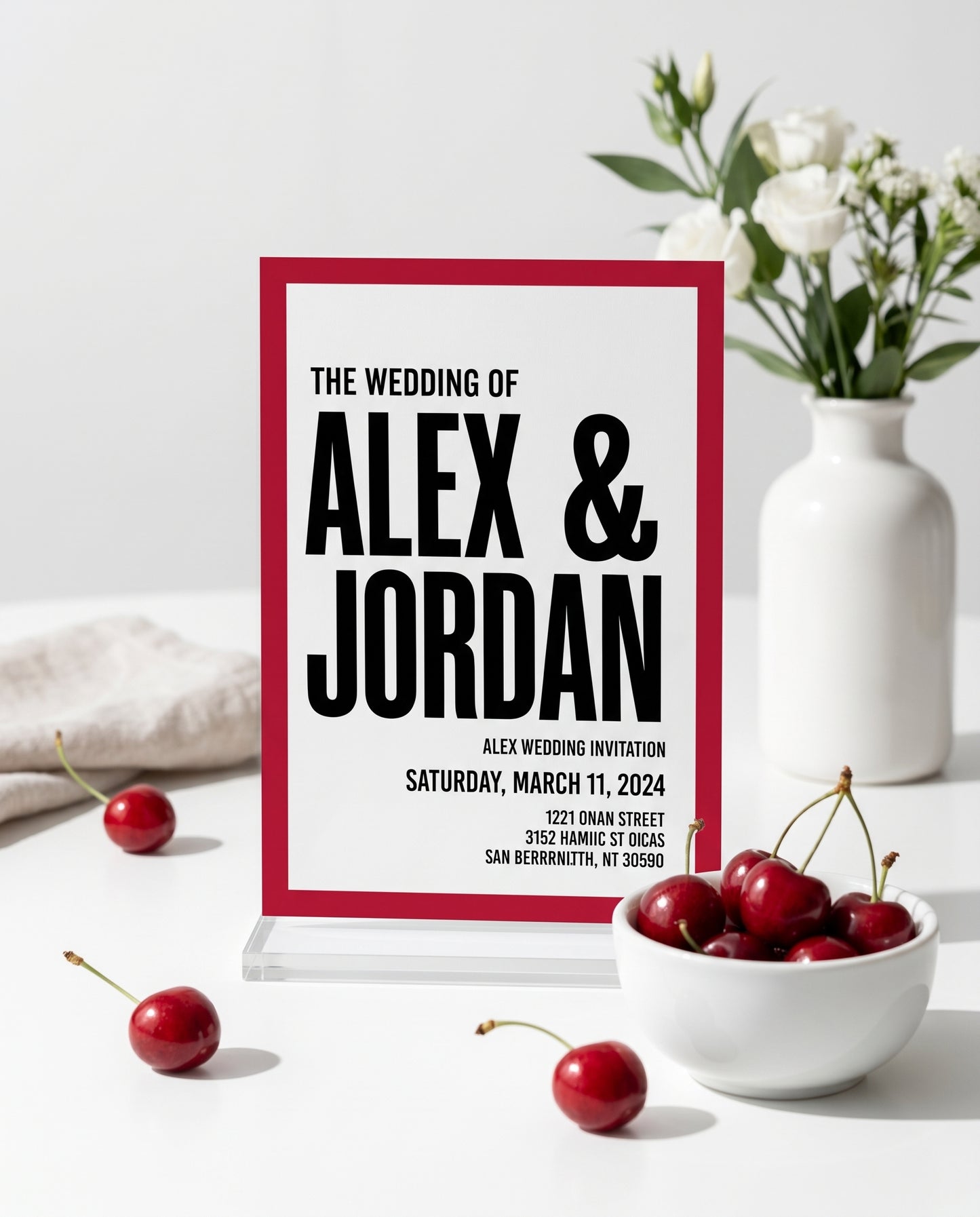 Cherry red wedding invitation displayed in a stand with cherries